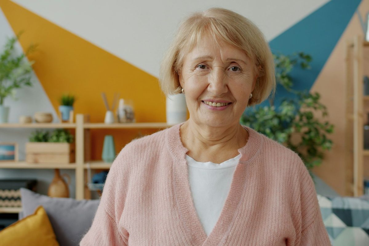 An older woman smiles in her living room.