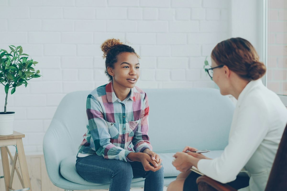 A young woman talks with a counselor in a bright office.