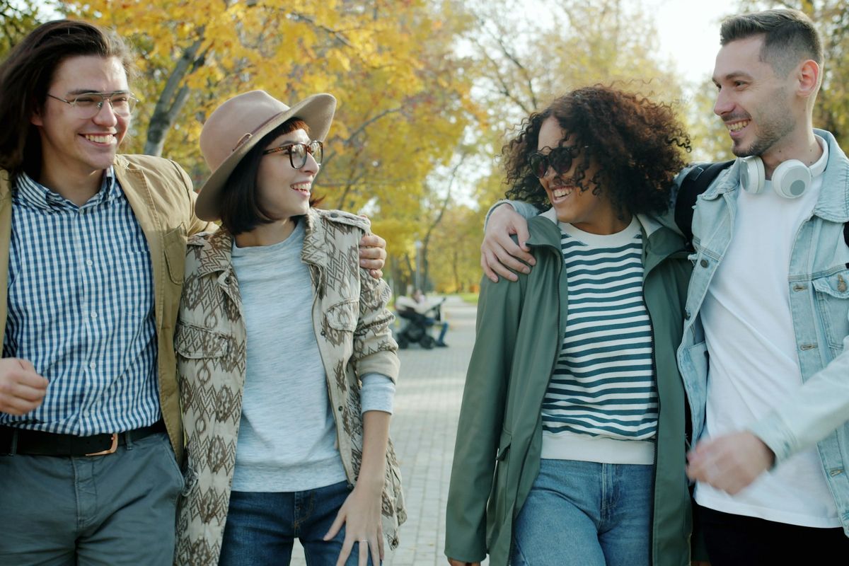 Four friends walk together in a park.